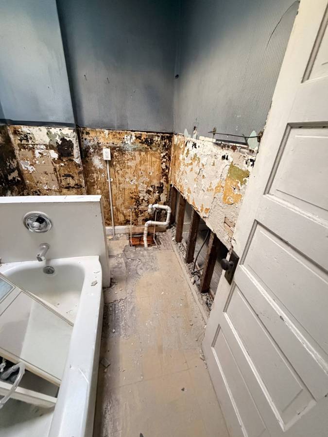 Bathroom with walls stripped and plumbing exposed